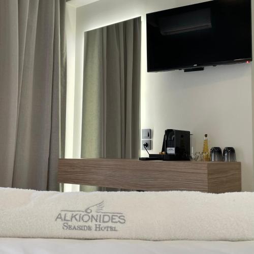 a hotel room with a bed with a television on the wall at Alkionides Seaside Hotel in Plataniás