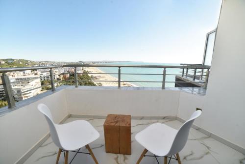 a balcony with two white chairs and a table at Beachfront Marilyn in Durrës