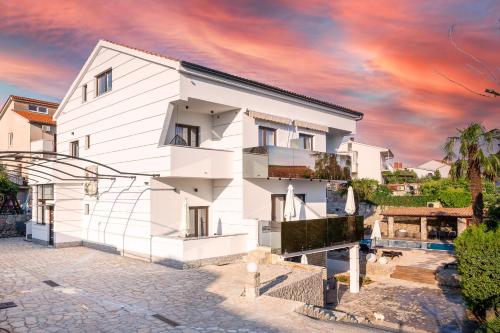 a white house with a sunset in the background at Villa Palma Krk in Krk