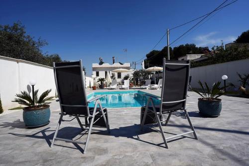 2 sillas sentadas frente a una piscina en Villa Giulia, en Marinella di Selinunte