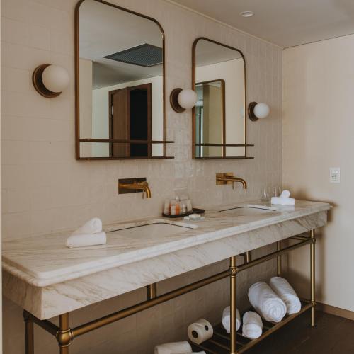 a bathroom with two sinks and two mirrors at Costanero Hotel Montevideo - MGallery Collection in Montevideo