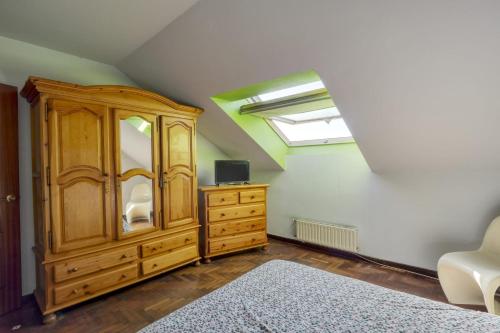a bedroom with a wooden cabinet and a skylight at Habitaciòn independiente con cama doble en dúplex in A Coruña