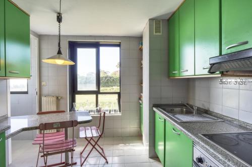 a kitchen with green cabinets and a table and chairs at Habitaciòn independiente con cama doble en dúplex in A Coruña