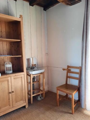 Cette chambre comprend une chaise en bois et une table. dans l'établissement Maison Spacieuse avec du Charme - Tout proche de la mer, à Cancale