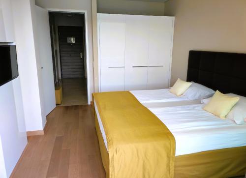 a bedroom with a large bed with a yellow blanket on it at Silba - Luxury Apartment in Rabac