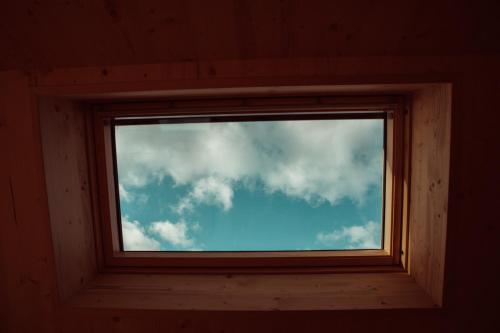 a window in a wooden cabin with a cloudy sky at Auszeit Tollensesee in Groß Nemerow