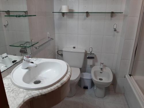 a white bathroom with a sink and a toilet at Pensión A Fonte in Caldas de Reis