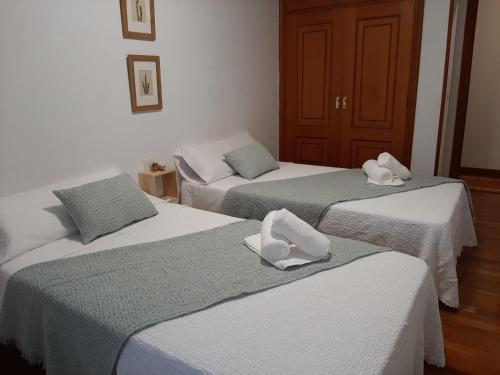 two beds with towels on them in a room at Pensión A Fonte in Caldas de Reis