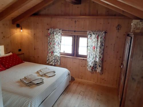 sypialnia w drewnianym domku z łóżkiem i oknem w obiekcie Piccolo e accogliente rascard CIR 0060 w mieście Champoluc