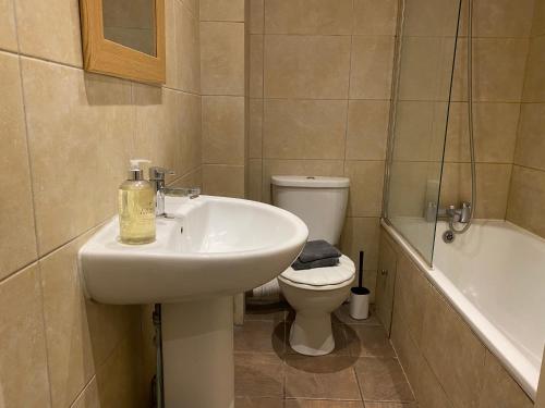 a bathroom with a sink and a toilet and a tub at Walpole Bay Apartment in Cliftonville