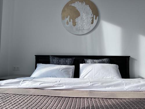 a bed with white sheets and a clock on the wall at Apartment in AXIS TOWERS, Tbilisi business center in Tbilisi City