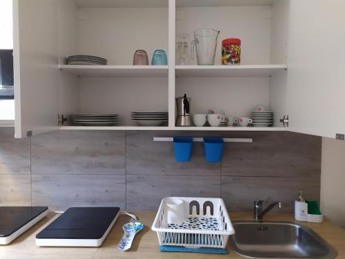 a kitchen counter with a sink and a dish drying rack at Le casette di Frà al Bondì in Santa Severa