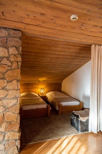 - 2 lits dans une chambre avec un mur en pierre dans l'établissement Grand chalet convivial avec sa piscine intérieure, à Serraval