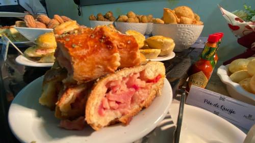 a sandwich on a plate on a table with other foods at Herval Park Hotel in Ponta Porã