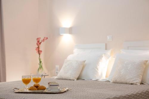 Una cama con dos vasos de zumo de naranja y una bandeja de comida. en Centrale Lefkada old town, en Lefkada