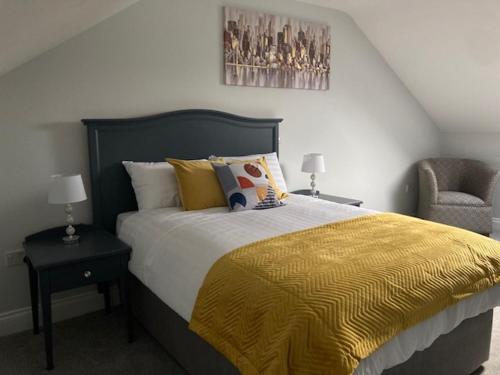 um quarto com uma cama com um cobertor amarelo e uma cadeira em Lir Lodge em Castlepollard