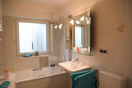 a bathroom with a sink and a mirror and a tub at Ferienwohnung Gipfelglück in Oberammergau