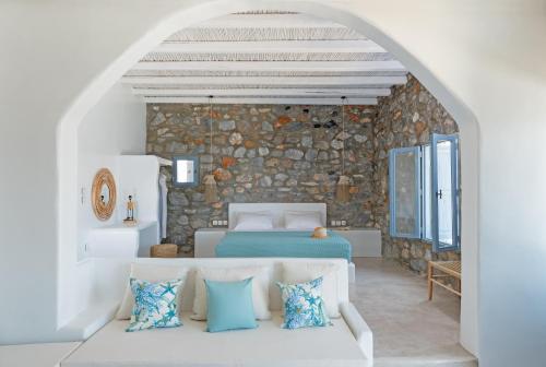 a bedroom with a bed and a stone wall at Nisides Suites in Livadi Astypalaias