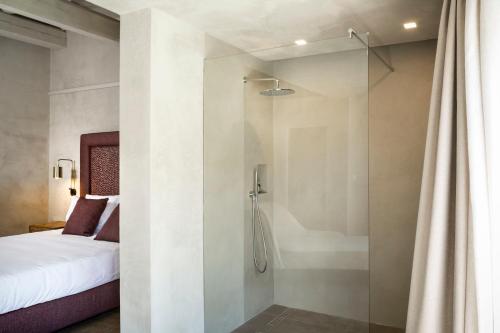 a bathroom with a shower with a bed and a glass door at Stazzo Lu Ciaccaru in Arzachena