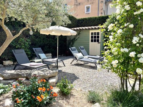 a patio with chairs and an umbrella and some flowers at B&B Temps Suspendu Provence in Pernes-les-Fontaines