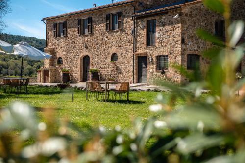 a stone building with chairs and a table in front of it at Tenuta Il Cicalino in Massa Marittima