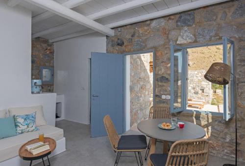 a living room with a stone wall and a table and chairs at Nisides Suites in Livadi Astypalaias