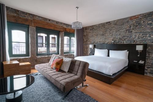 um quarto de hotel com uma cama e um sofá em Le Petit Hotel St Paul by Gray Collection em Montréal