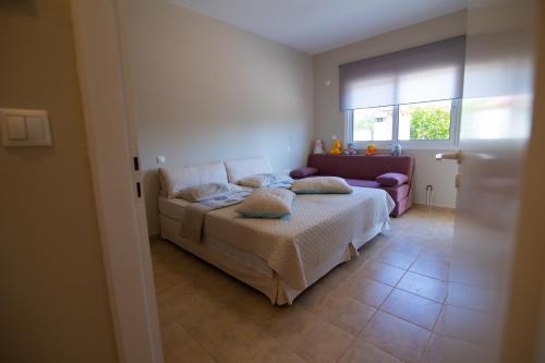 a bedroom with a bed and a couch and a window at Sunset Resort in Aiándion