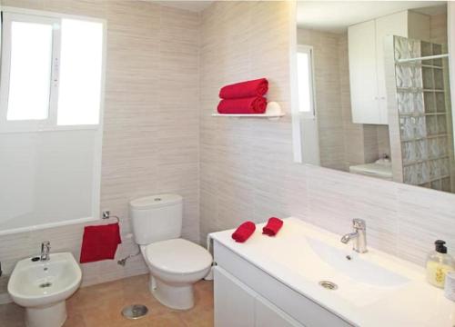 ein Bad mit einem WC und einem Waschbecken mit einem roten Handtuch in der Unterkunft Ático en playa Muchavista con vistas espectaculares a San Juan in Benimagrell