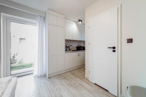 a white kitchen with white cabinets and a large window at Dobre smaki at Wczasowa8 sea resort in Sarbinowo