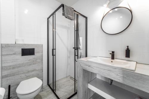 een badkamer met een toilet, een wastafel en een spiegel bij Dobre smaki at Wczasowa8 sea resort in Sarbinowo