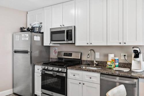 a kitchen with white cabinets and stainless steel appliances at Radiant Beach Block Condo Parking Patio in Brigantine