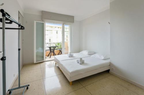 une chambre blanche avec un lit et un balcon dans l'établissement Superbe appartement avec balcon et belle vue sur la mer - Cannes - Welkeys, à Cannes