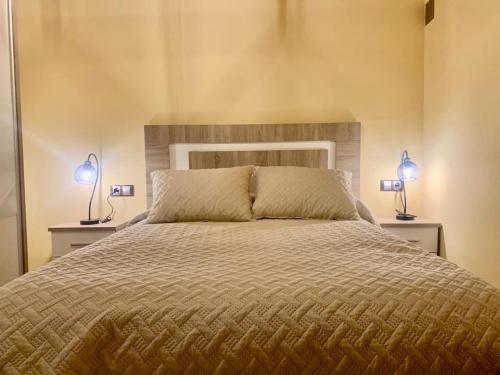 1 dormitorio con 1 cama con 2 lámparas en 2 mesas en Rincon de los artesanos, en Bedmar