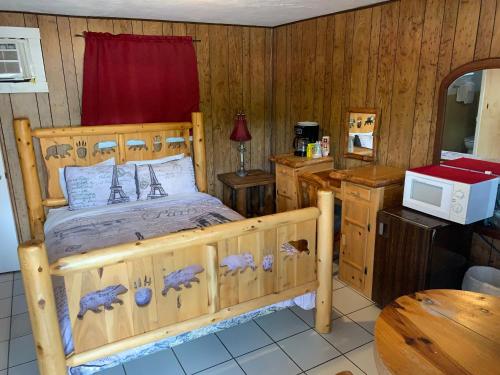 a bedroom with a wooden bed and a microwave at Phillips Historic Motel & Cottages in Robbinsville