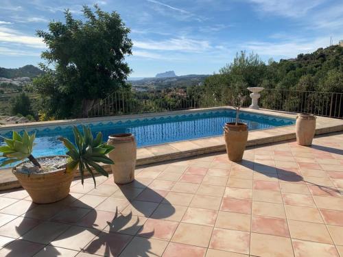 a swimming pool with potted plants on a patio at Finca la Jarra in Benitachell