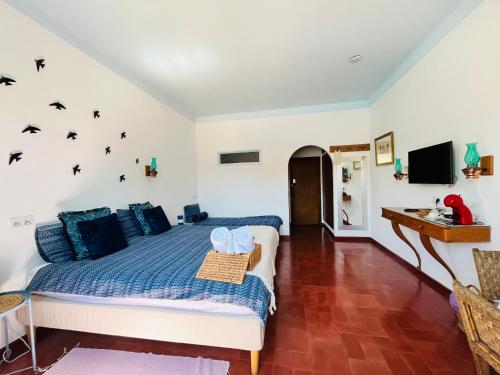 um quarto com uma cama com lençóis azuis e pássaros pretos na parede em Casa Santo António em São Brás de Alportel