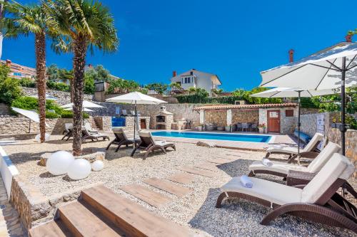 een villa met een zwembad en palmbomen bij Apartments Petra Krk in Krk