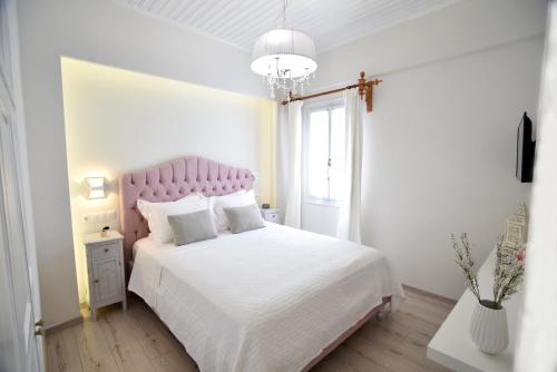 a white bedroom with a pink bed and a window at Kallisti the house at the port in Galaxidhion