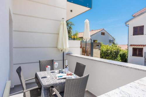a table and chairs on a balcony with an umbrella at Apartments Petra Krk in Krk