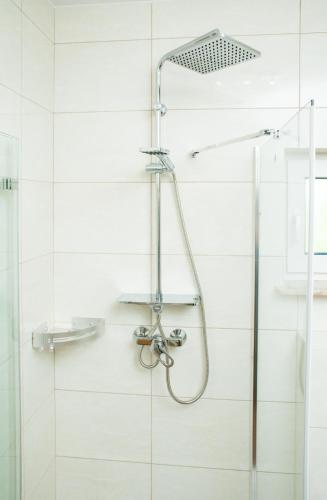 a shower in a bathroom with white tiles at Domki Nordic in Władysławowo