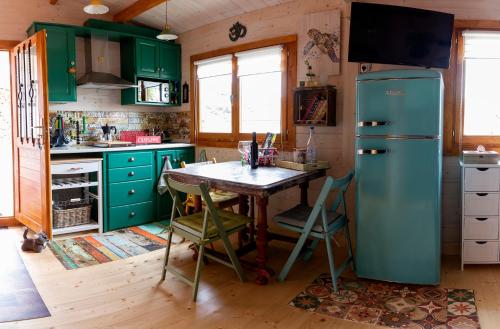 a kitchen with green cabinets and a table with a refrigerator at Cabaña IkiZen in Barbadillo del Pez