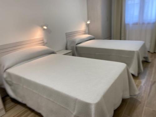 3 Betten in einem Hotelzimmer mit weißer Bettwäsche in der Unterkunft Apartamentos Torreones de Cartes in Cartes
