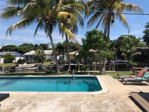 a swimming pool with a chair and palm trees at Modern Spanish Villa- Pool- By River-Tropical !!! in Fort Lauderdale