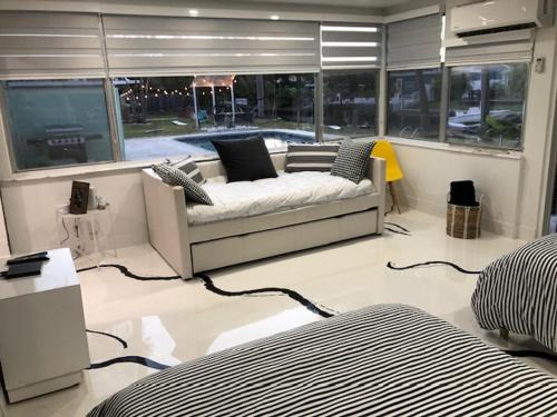 una sala de estar con sofá en una habitación con ventanas en Modern Spanish Villa- Pool- By River-Tropical !!!, en Fort Lauderdale