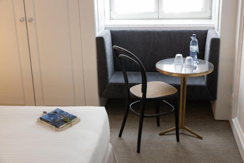a small table and a chair in a room at Lisboa Pessoa Hotel in Lisbon