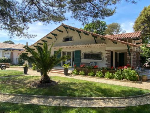 a house with a palm tree in the front yard at Villa de charme avec piscine à 500m des plages in Soorts-Hossegor