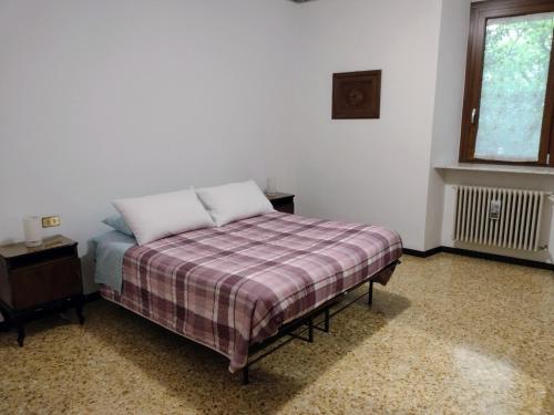 a bedroom with a bed with a plaid blanket and a window at Appartamento Teoperga in Sotto il Monte