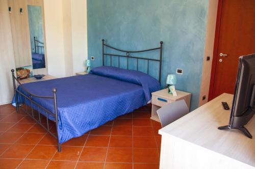 ein Schlafzimmer mit einem blauen Bett und einem TV in der Unterkunft La Casa sulla Collina in Altavilla Silentina