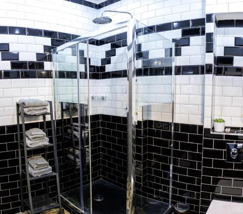 a glass shower in a bathroom with black and white tiles at Loft SSL insolite!!! in Gignac-la-Nerthe